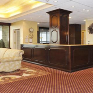 A stylish hotel lobby featuring a wooden reception desk and cozy seating area.