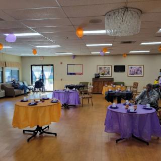 A decorated indoor space set up for a party with purple and orange accents.