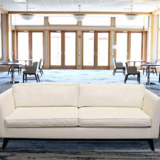 A modern cream-colored couch placed in a spacious lounge area with large windows.