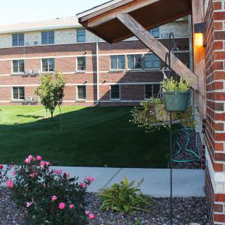 A brick building with a garden and flowers along a pathway.