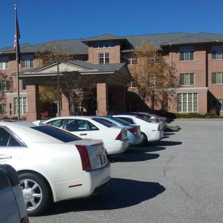 A row of parked cars in front of a brick building on a sunny day.