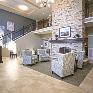 A modern hotel lobby with a cozy seating area around a stone fireplace.