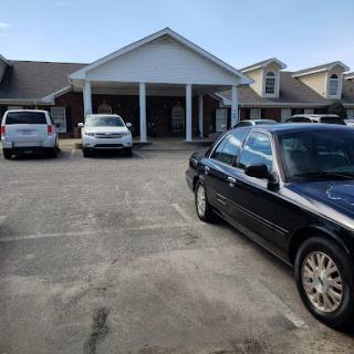 A view of a parking lot featuring a black car and several white vehicles in front of a building.