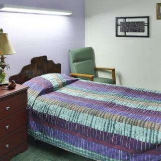 A cozy bedroom with a colorful quilt on the bed and soft lighting.