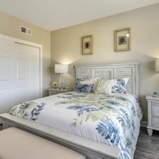 A cozy bedroom with a floral-patterned bedspread, complemented by matching pillows, nightstands, and lamps.