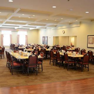 An empty dining hall with neatly arranged tables and chairs, ready for an event.