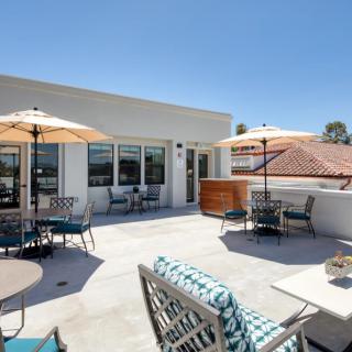 A modern outdoor patio with umbrellas and furniture on a sunny day.