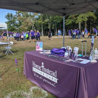 A colorful community event featuring an information booth under a tent, promoting awareness and engagement.