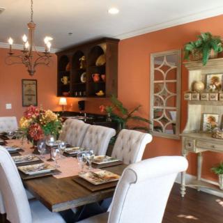An elegantly decorated dining room featuring a beautifully set table, orange walls, and stylish furniture.