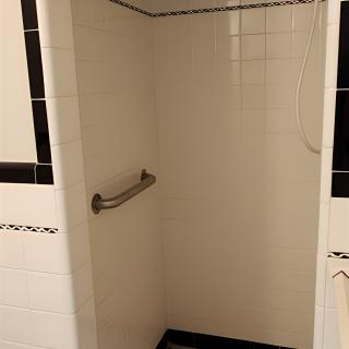 A tiled shower area with a grab bar installed on the wall.