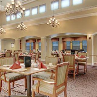 A well-lit dining area with elegant chandeliers and neatly arranged tables and chairs.