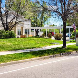 A suburban house with a well-maintained lawn and trees under a clear blue sky.