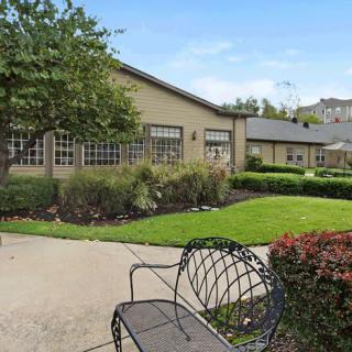 A serene outdoor area featuring a building, garden, and bench.