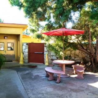 A sunny patio area with a table and umbrella surrounded by trees.