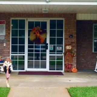 A building entrance adorned with fall decorations, including a wreath and scarecrow.