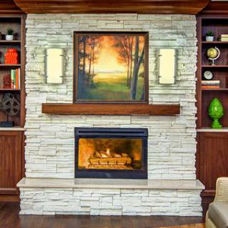 A cozy living room features a stone fireplace with an artwork above it, flanked by built-in wood shelves and soft lighting.