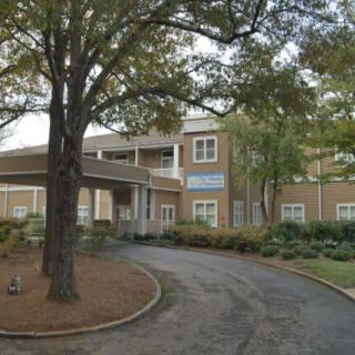 A view of a building entrance with a circular driveway and surrounding trees.