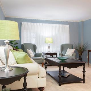 A stylishly decorated living room featuring a comfortable sofa, two armchairs, elegant lamps, and a wooden coffee table with decorative items.