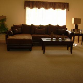A cozy living room featuring a large sectional sofa and a coffee table, illuminated by natural light from a window.