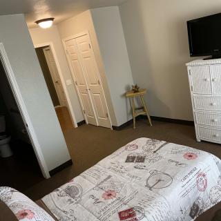 A cozy bedroom with a neatly made bed, dresser, and television.