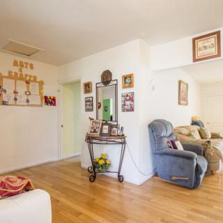A cozy living room with an armchair, wall decor, and wooden flooring.