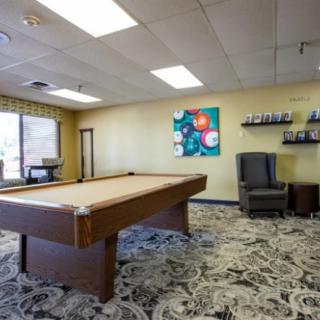 A spacious game room featuring a pool table, modern artwork, and comfortable seating.