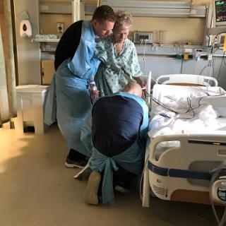 Family members offering support to a patient in a hospital room.