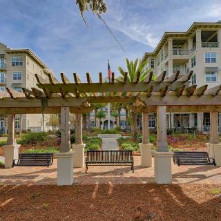 A view of an outdoor area featuring a pergola and benches in front of an apartment complex.