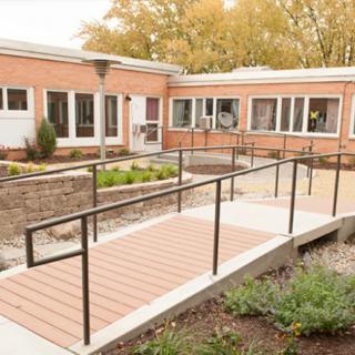 A brick building with a ramp entrance, surrounded by autumn foliage.