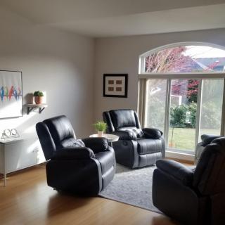 A cozy living room with black recliner chairs and a large window letting in natural light.