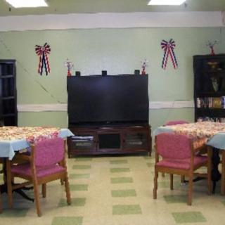 A communal living space with a large television, tables, and chairs adorned with decorations.