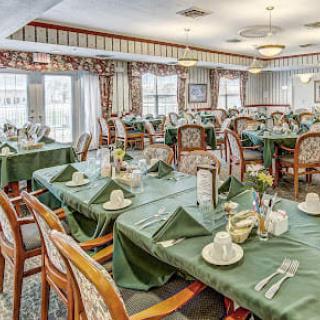 An elegant dining room with neatly set tables and green tablecloths.