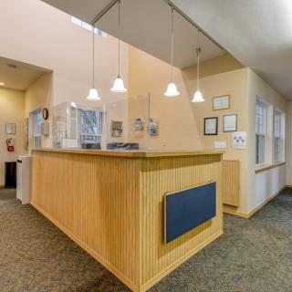 A modern reception desk with wood paneling and pendant lighting in an office lobby.