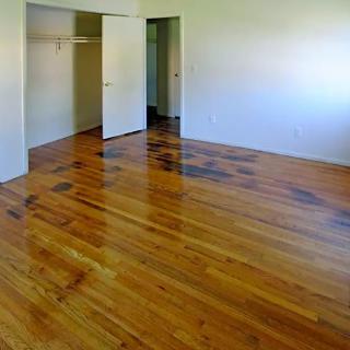 An empty room with a polished wooden floor and an open closet door.