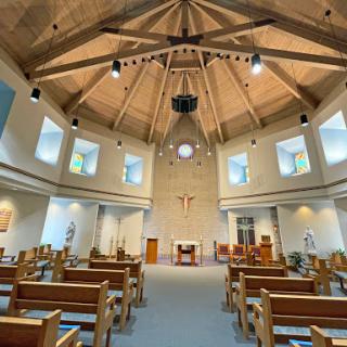 Interior view of a modern church showcasing its beautiful wooden ceiling and serene atmosphere.