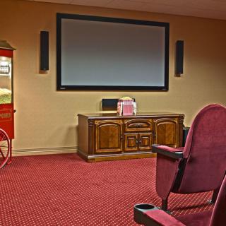 A cozy home theater setup with a large screen, popcorn machine, and comfortable red seating.