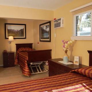 A cozy bedroom featuring twin beds, wood furniture, and decorative elements such as paintings and a vase with flowers.