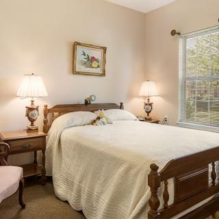 A cozy bedroom with a wooden bed, nightstands, and two lamps by the window.