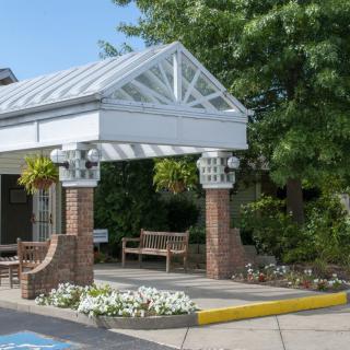 A covered pavilion entrance with benches and flower landscaping on a sunny day.