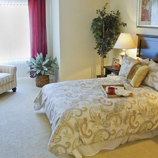 A cozy bedroom with a comfortable bed, decorative pillows, and elegant furnishings.