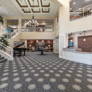 A spacious lobby with modern decor, featuring a grand piano, chandelier, and reception desk.