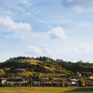 A picturesque view of a village nestled among rolling hills under a clear blue sky.