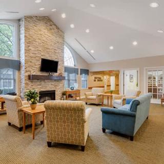A cozy living room with a stone fireplace, multiple seating options, and large windows providing natural light.
