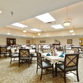 A spacious dining room with neatly arranged tables and chairs, illuminated by ceiling lights.