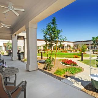 A beautifully landscaped courtyard with a covered seating area and garden under a bright blue sky.