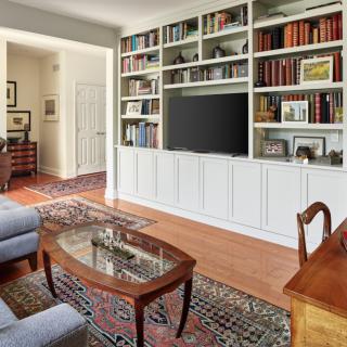 A cozy living room with a built-in bookshelf, television, and elegant wooden furniture.