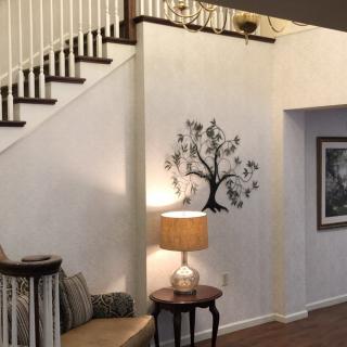 A cozy living room featuring a staircase, wall art, and comfortable seating with a lamp.