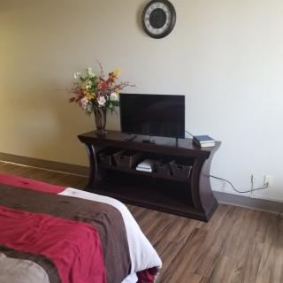 A cozy bedroom with a small television on a wooden stand, accompanied by a decorative flower vase.