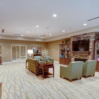 A cozy living room with comfortable seating, a television above a fireplace, and elegant decor.