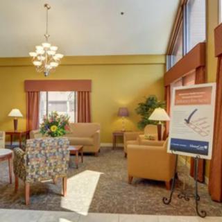 A cozy lobby area with comfortable seating, a chandelier, and large windows.